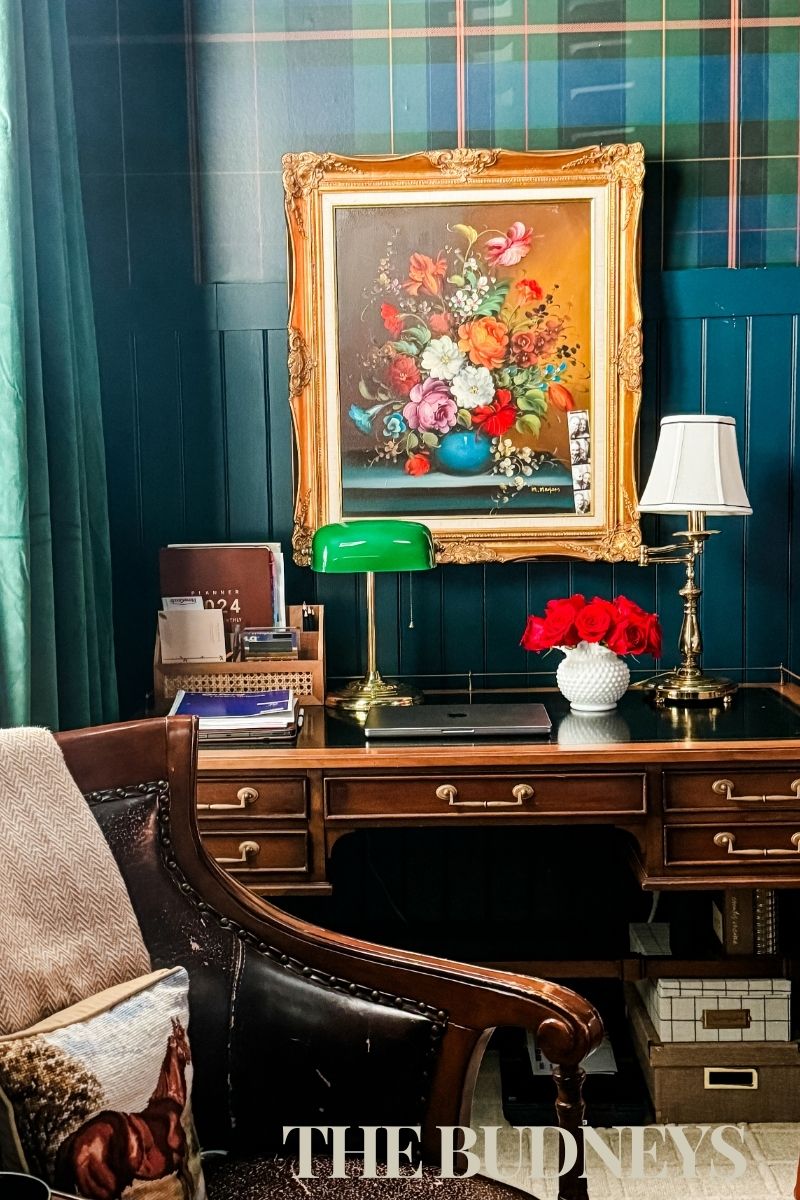 This photo shoes an antique wood desk and chair, styled with vintage brass lamps, floral oil painting with gold frame, and needlepoint equestrian pillow.